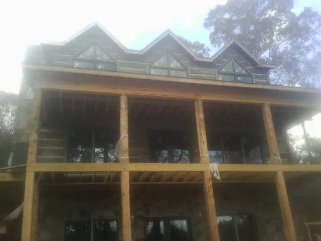 Dormers and porch framing on a large log home under construction — Roof Coating work by our crew in Tatums