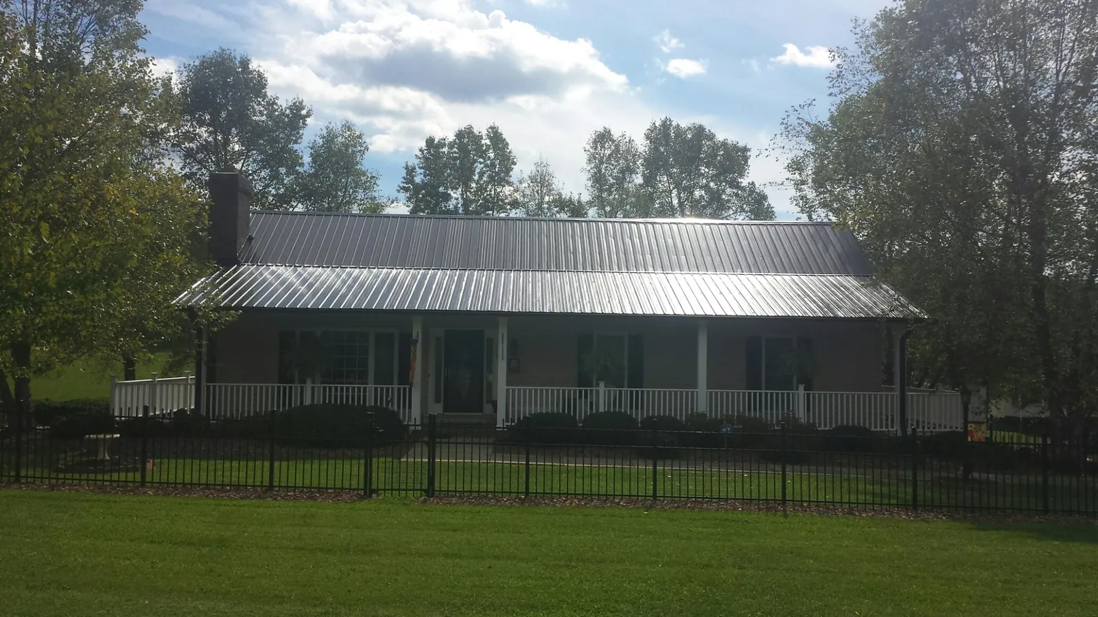 Gray metal roof on a brick ranch with a full width front porch in Tatums