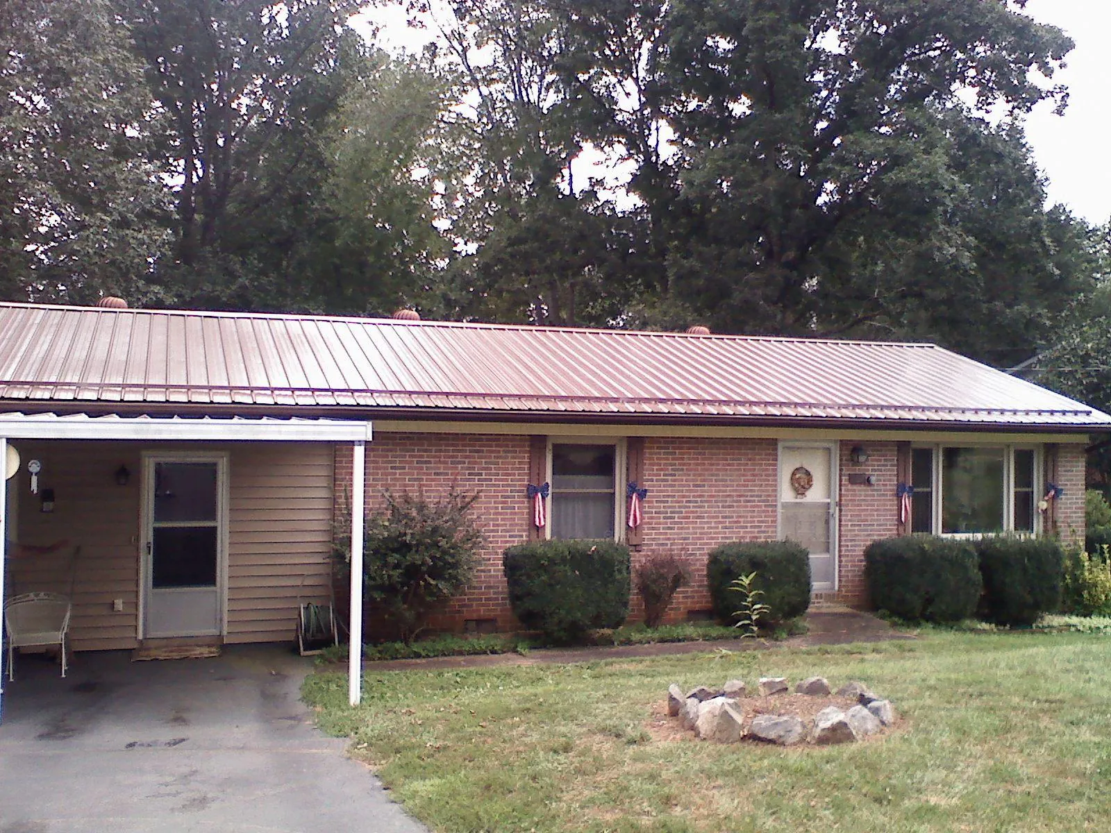 Bronze metal roof and carport on a brick ranch home — Roof Repair work by our crew in Tatums