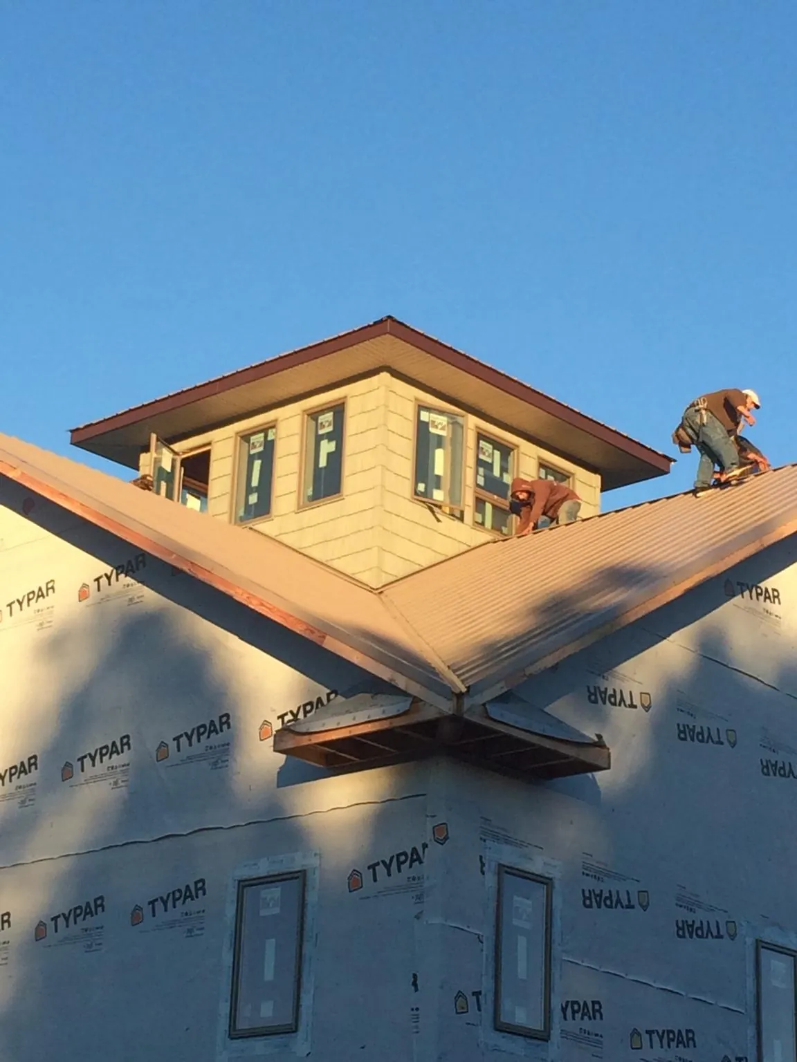 Roofers working around a rooftop cupola on a new metal roof at sunset — Roof Waterproofing in Tatums by Roofing Brothers